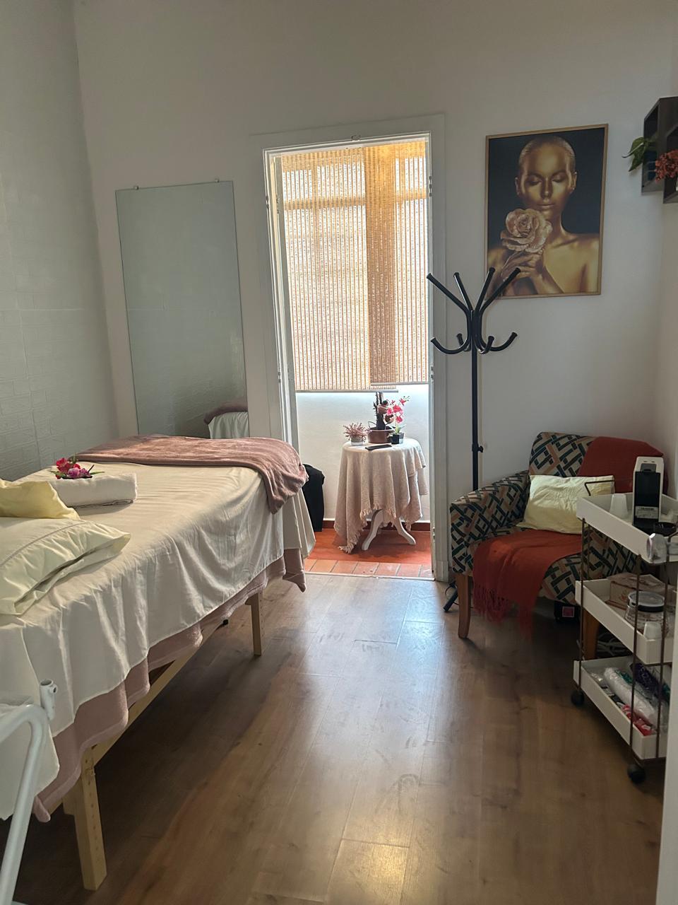 Sala de estética e massagem do Espaço Elegance, com maca preparada, espelho e poltrona de descanso