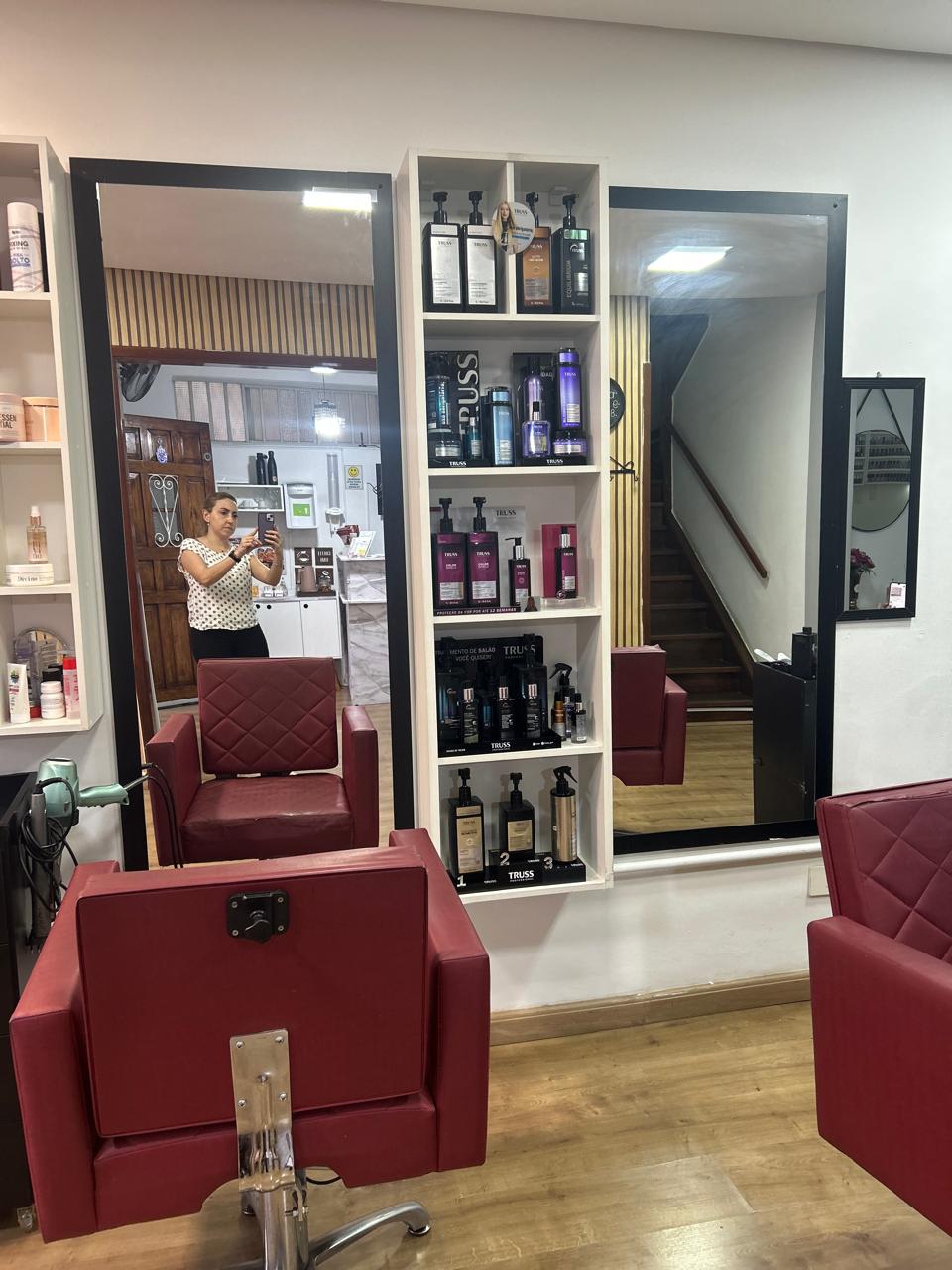 Área de cabelo do Espaço Elegance, com cadeiras, espelhos e produtos de tratamento capilar